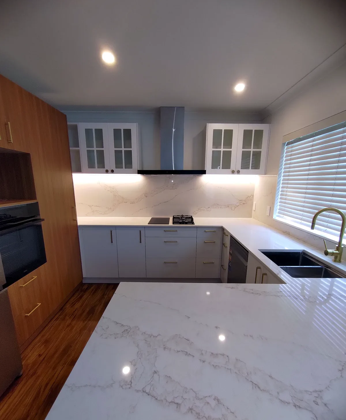 Kitchen renovation with marble waterfall benchtop and gold tapware — Green Bay, Auckland