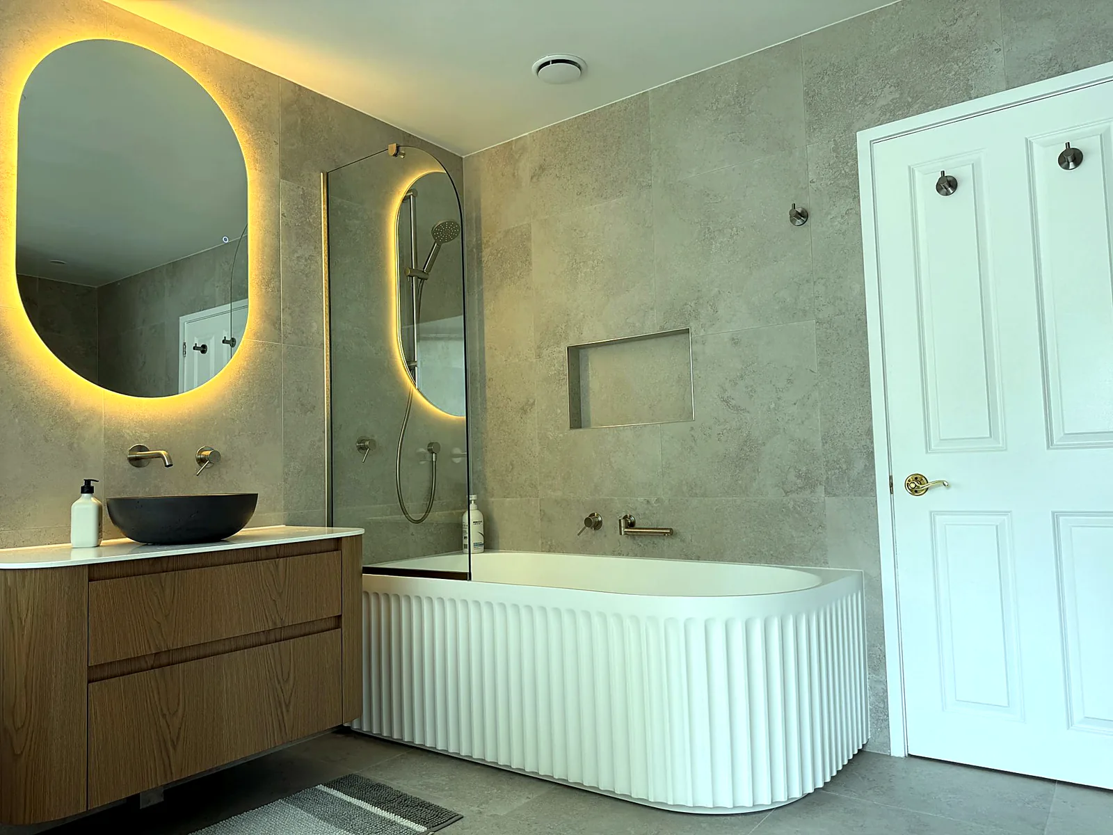 Luxury bathroom with fluted freestanding bath and backlit mirrors — Remuera, Auckland